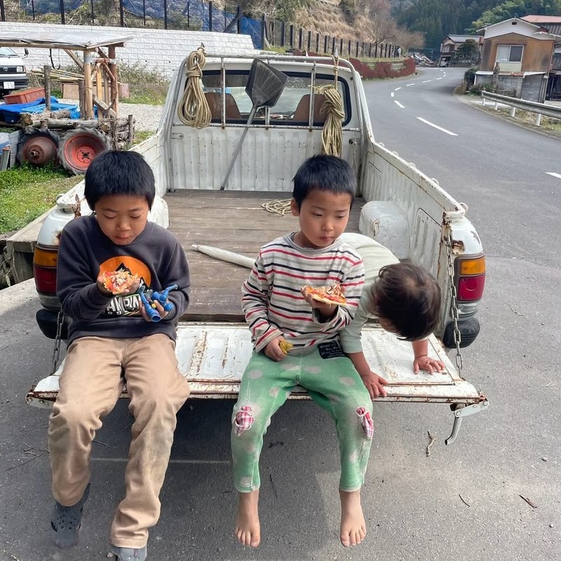 軽トラの荷台でピザを食べる子どもたち
